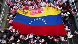 Sejumlah warga mengibarkan bendera nasional Venezuela saat mengikuti pawai yang diselenggarakan pemerintah untuk meningkatkan kesadaran terhadap kanker payudara dalam rangka Bulan Peduli Kanker Payudara atau Pink Month di Caracas, Venezuela, Kamis (22/10/2026). (AP Photo/Pedro Mattey)