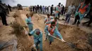 Dilansir Al-Arabiya dan AFP, Kamis (23/11/2023), berbalut terpal biru, puluhan jenazah tersebut diturunkan dengan tandu ke dalam lubang berpasir yang perlahan diperbesar dengan alat penggali. Beberapa jenazah berukuran anak-anak. (AP Photo/Mohammed Dahman)