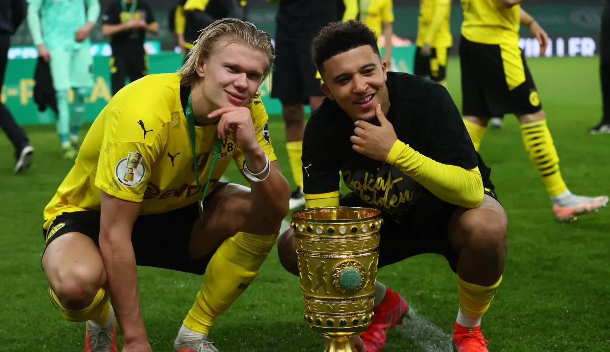 Gelandang Dortmund, Jadon Sancho bersama penyerang Erling Braut Haaland berpose dengan trofi setelah memenangkan pertandingan final Piala Jerman (DFB Pokal) melawan RB Leipzig di Berlin pada 13 Mei 2021. (AFP/ Pool/Martin Rose)
