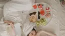 Sama-sama memakai robe putih, keduanya berpose di atas tempat tidur sambil memanjakan diri dengan buku dan makanan. (IG: @danitasigarlaki)