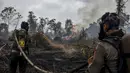 Polisi yang mengenakan perlengkapan pemadam kebakaran memadamkan kebakaran lahan gambut di Tambang, Kabupaten Kampar, Provinsi Riau, Selasa,  25 Agustus 2026. (AFP/ Wahyudi)