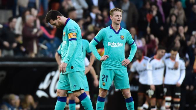Pemain Barcelona, Lionel Messi dan Frenkie de Jong, terlihat lemas saat Valencia berhasil mencetak gol ke gawang Barcelona. Valencia menang 2-0 atas Barcelona di Mestalla, dalam laga jornada 21 La Liga, Sabtu (25/1/2020). (Jose Jordan/AFP)