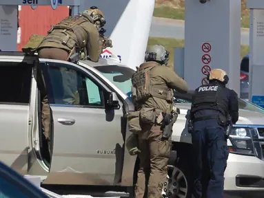 Petugas Polisi Mounted Royal Kanada mengelilingi seorang tersangka di sebuah pom bensin di Enfield, Nova Scotia, Minggu (19/4/2020). Polisi Kanada mengatakan beberapa orang tewas ditambah tersangka setelah penembakan mengamuk di provinsi Nova Scotia. (Tim Krochak/The Canadian Press via AP)