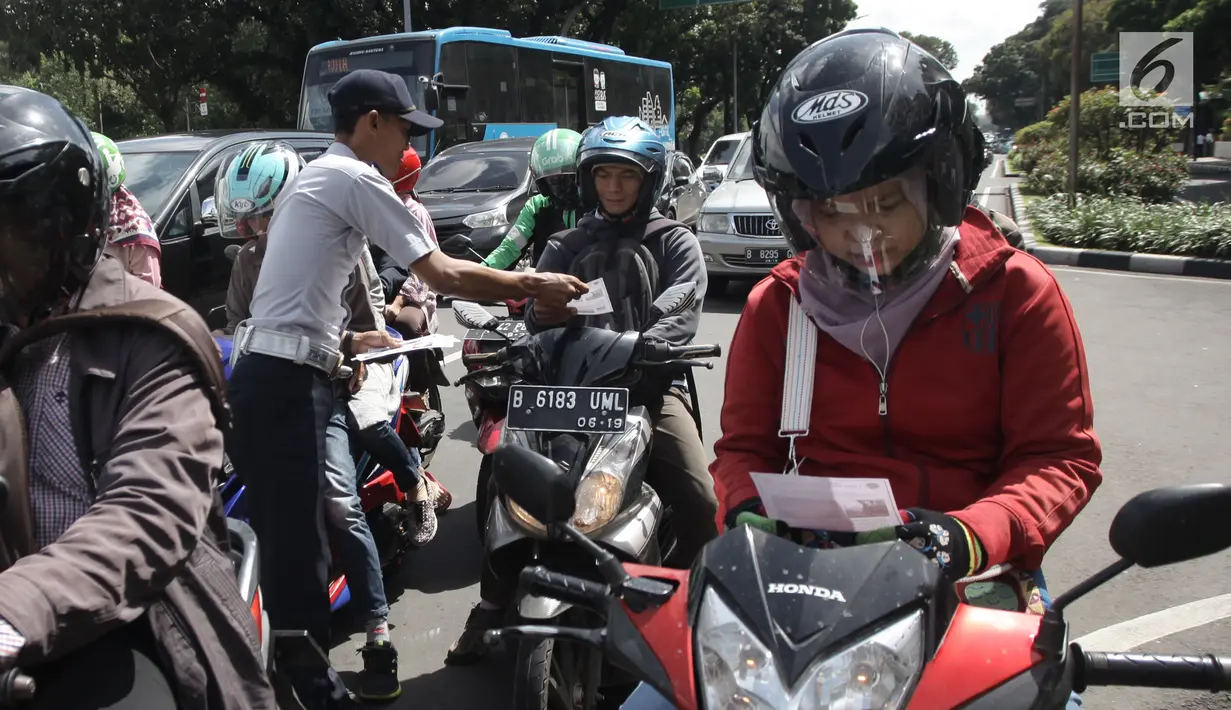 Petugas Dishub melakukan sosialisasi lajur khusus sepeda motor di Jalan MH Thamrin, Jakarta, Senin (29/1). Pengendara sepeda motor yang melintas di luar lajur khusus tersebut akan diberi sanksi sesuai ketentuan yang berlaku. (Liputan6.com/Arya Manggala)