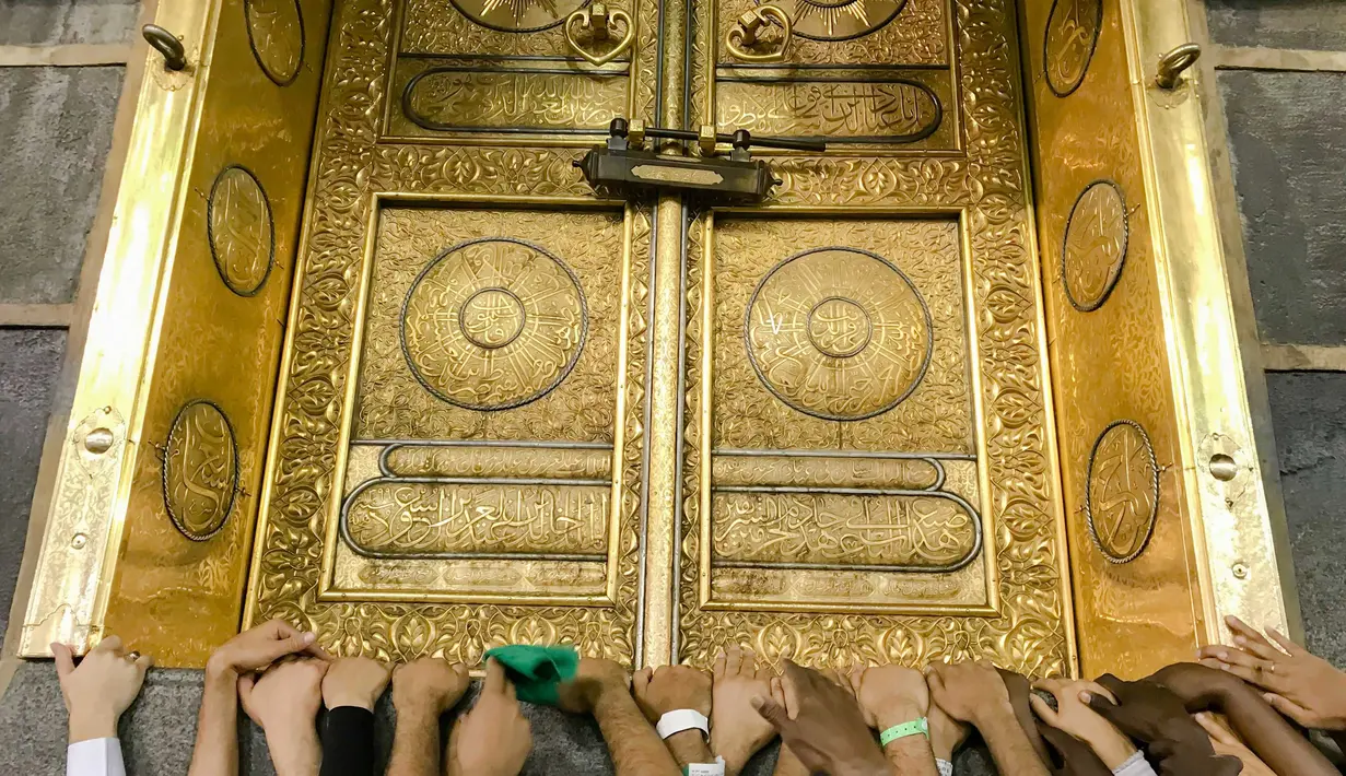 Umat muslim memagang pintu Kakbah di Masjidil Haram, Mekah, Arab Saudi, Jumat (17/8). Kakbah menjadi kiblat umat muslim seluruh dunia saat melaksanakan salat. (AP Photo/ Dar Yasin)