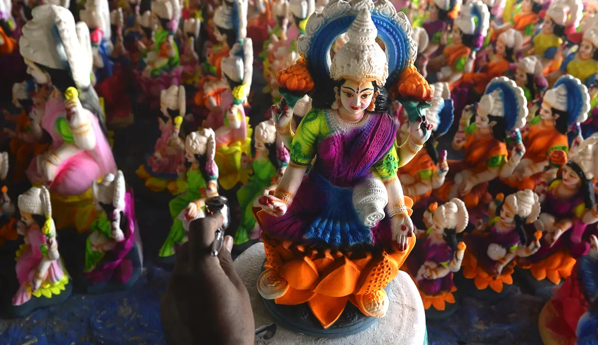 Seorang perajin mengecat patung dewi Hindu Lakshmi di sebuah lokakarya menjelang Diwali, festival lampu Hindu di pinggiran Hyderabad (28/10/2021). Diwali merupakan festival cahaya yang dianggap banyak orang sebagai awal tahun baru. (AFP/Noah Seelam)