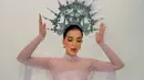 Dengan kedua tangan terangkat dan mata menunduk, Tasya memamerkan potongan lengan renda yang menjuntai panjang. Gaun lilac dengan korset satin yang membentuk siluet, rok bergaya draping, dan crown silver bertabur mutiara menegaskan kesan anggun sekaligus kuat. [@tasyafarasya]