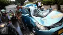 Petugas bersama sopir taksi memeriksa kondisi taksi yang tertimpa pohon tumbang di dekat Hotel Millenium, Jalan Taman Kebon Sirih, Jakarta, Selasa (30/8). Pohon itu roboh menimpa taksi bernopol B 1606 TTC hingga ringsek berat. (Liputan6.com/Faizal Fanani)