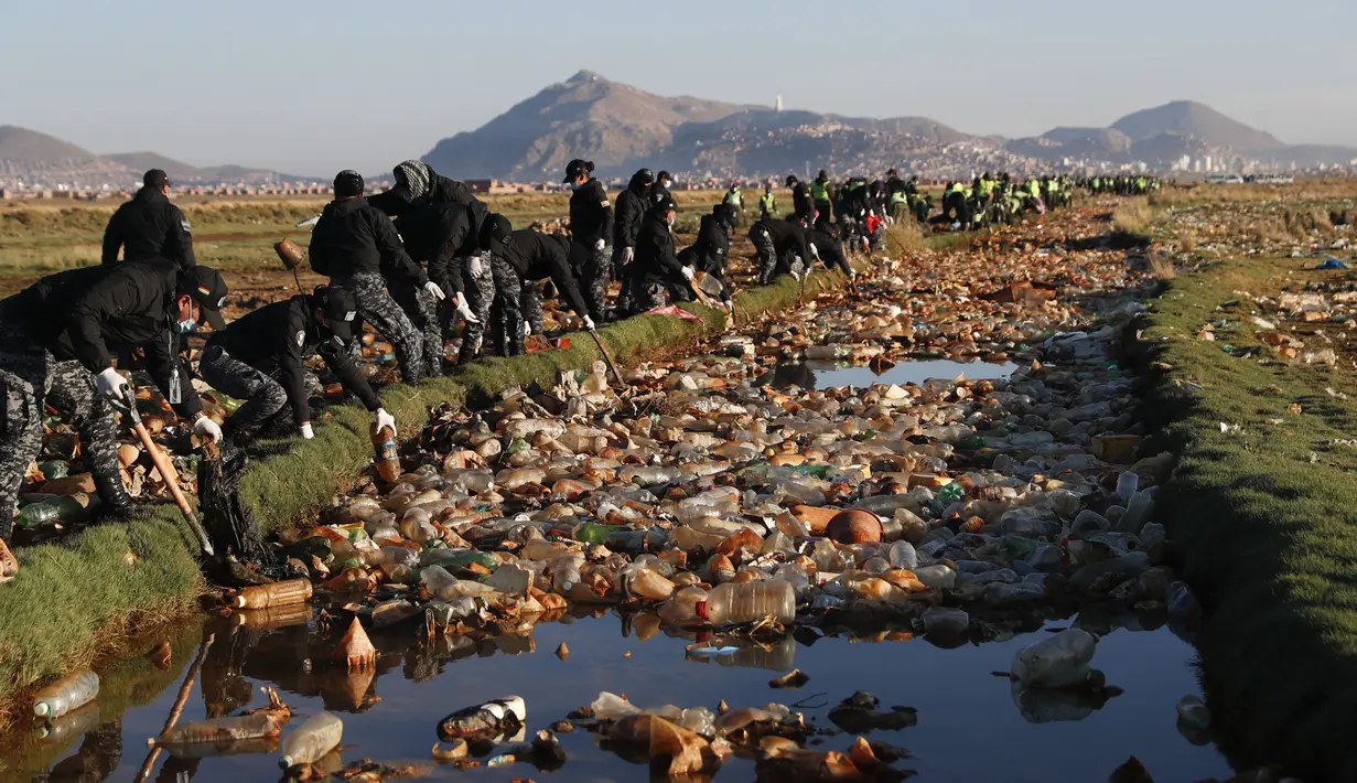 Petugas polisi membuang sampah dari Sungai Tagaret, yang mengalir ke Danau Uru Uru, dekat Oruro, Bolivia, Rabu (7/4/2021). Operasi pembersihan dimulai hari Rabu dalam upaya mengembalikan danau ke keindahan alamnya yang telah dibanjiri sampah plastik dan limbah buatan manusia lainnya. (AP/Juan Kari)