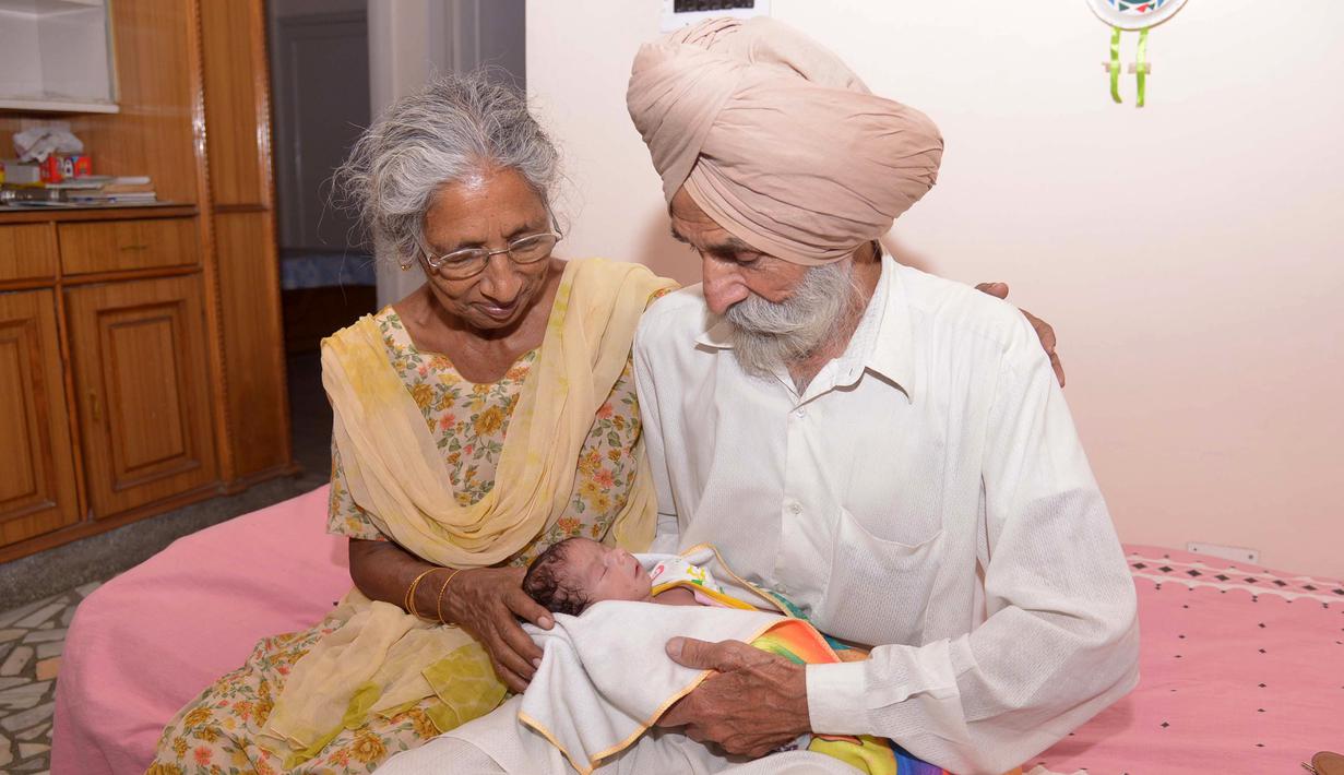 Daljinder Kaur (kiri) bersama sang suami Mohinder Singh Gill saat mengasuh anak mereka di Amritsar, India, Rabu (11/5). Bayi yang lahir bulan lalu ini dinamai Armaan.( NARINDER NANU / AFP)