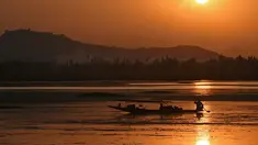 Seorang nelayan Kashmir mengayuh perahunya saat matahari terbenam di danau Dal di Srinagar, India (12/9). Danau Dal dijuluki sebagai Jewel in the Crown of Kashmir atau Srinagar Jewel. (AFP Photo/Tauseef Mustafa)