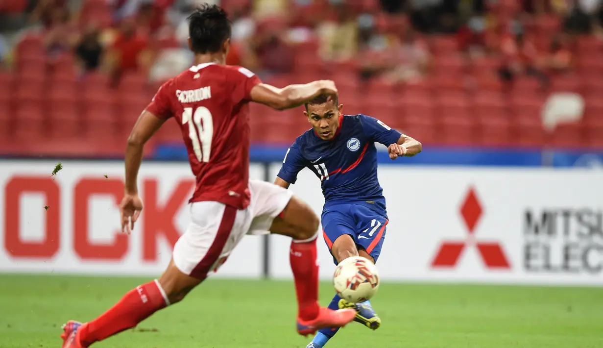 Penyerang Timnas Singapura, Hafiz Nor (kanan) berusaha menembak bola dari kawalan bek Indonesia, Fachrudin Aryanto pada pertandingan leg kedua semifinal Piala AFF 2020 di National Stadium, Sabtu (25/12/2021). Indonesia akan bertemu antara Thailand dan Vietnam di babak final. (AFP/Roslan Rahman)