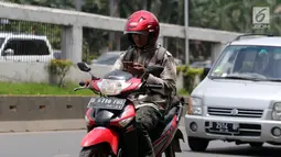 Pengendara menggunakan telepon seluler saat melaju dengan sepeda motornya di Jalan Gatot Subroto, Jakarta, Kamis (8/3). Dirlantas Polda Metro Jaya akan menindak orang yang menggunakan telepon seluler saat aktivitas lalu lintas.(Liputan6.com/Arya Manggala)