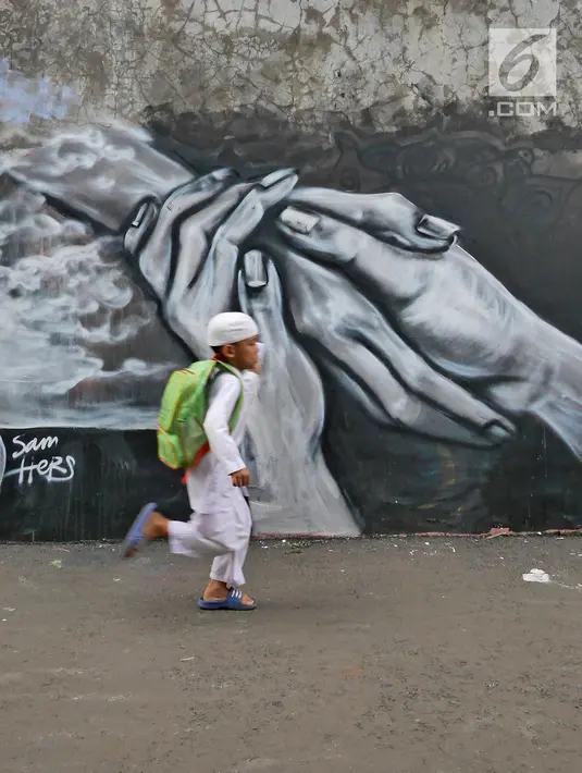Seorang bocah berlari di depan dinding berhias mural bertema Islami di Gang Abdul Jabar, Jagakarsa, Jakarta, Senin (28/5). (Liputan6.com/Herman Zakharia)