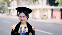 Penantian 3,5 tahun, kebahagiaan tak henti terpancar di wajah Vanessa Audy berfoto dengan atribut lengkap wisuda mulai dari toga, jubah, dan selempangnya. Kuliah di Unair, Surabaya adalah impian Vanessa Audy sejak lama. Lewat instastory terbarunya, Audy ungkap jika ia dulu selalu senang jika melewati Unair ketika jalan-jalan ke Surabaya. Audy juga sering sebut jika Unair adalah kampusnya meski saat itu belum menjadi mahasiswa. (Liputan6.com/IG/@audyvanessa)