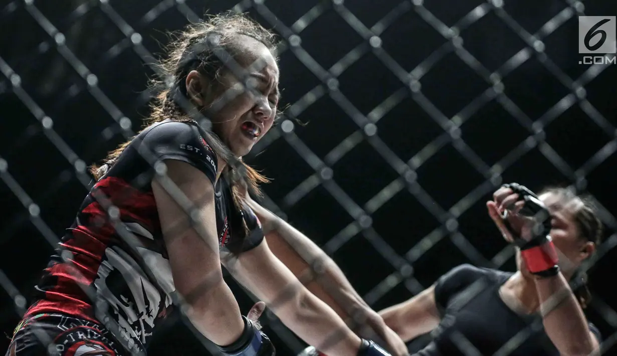 Petarung putri Malaysia, Audreylaura Boniface (kiri) menahan tendangan dari petarung Indonesia, Priscilla Hertati Lumban Gaol (kanan) saat berlaga pada partai pertama One Championship di Jakarta, Sabtu (20/1). (Liputan6.com/Faizal Fanani)