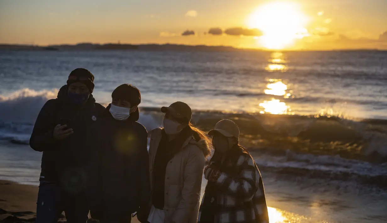 Orang-orang berkumpul di Pantai Selatan Chigasaki untuk menyaksikan matahari terbit pada Hari Tahun Baru di Prefektur Kanagawa, barat daya Tokyo (1/1/2021). (AFP/Philip Fong)