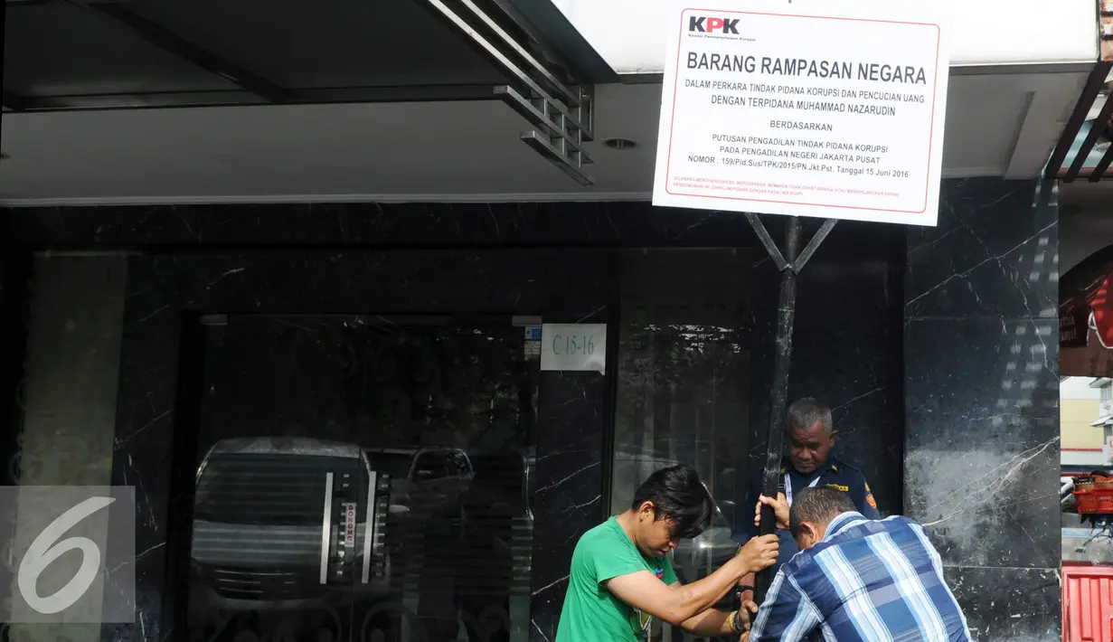 Pekerja menancapkan plang segel ruko Nazaruddin yang berada di Wijaya Grand Center, Jakarta Selatan, Senin (28/11). Ruko tersebut masuk dalam daftar kekayaan Nazaruddin yang dirampas negara. (Liputan6.com/Helmi Affandi)