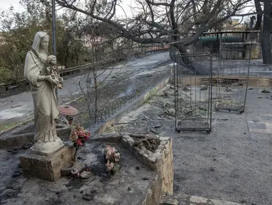 Foto yang diambil pada 26 Juli 2023 ini menunjukkan patung Virgin Mary di pom bensin area Tindari North Service yang terbakar, di jalan tol Messina - Palermo di kota Oliveri, provinsi Messina, Sisilia, setelah kebakaran semalam melanda distrik tersebut. (Photo by Giovanni ISOLINO / AFP)