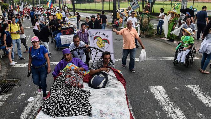 Warga Kolombia turun ke jalanan dan bermalas-malasan di atas tempat tidur dalam pawai untuk merayakan Hari Kemalasan Sedunia di Itagui, dekat Medellin, Minggu (19/8). Perayaan ini juga selalu penuh dengan antusiasme masyarakat. (AFP/JOAQUIN SARMIENTO)