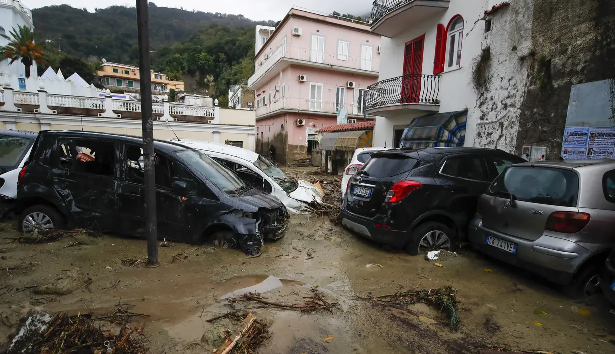Mobil-mobil yang rusak terlihat di jalan yang banjir setelah hujan deras memicu tanah longsor yang meruntuhkan bangunan dan menyebabkan 12 orang hilang, di Casamicciola, di pulau Ischia, Italia selatan, Sabtu, 26 November 2022. (AP Photo/Salvatore Laporta)