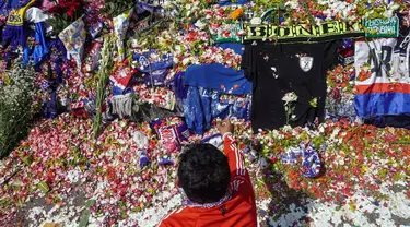 Seorang pria melakukan tabur bunga di luar Stadion Kanjuruhan, Malang, Jawa Timur, Selasa (4/10/2022). Polri menjatuhkan sanksi kepada 10 anggota polisi dan menyelidiki 18 orang lainnya buntut tragedi kerusuhan yang menewaskan 125 orang di Stadion Kanjuruhan. (AP Photo/Dicky Bisinglasi)