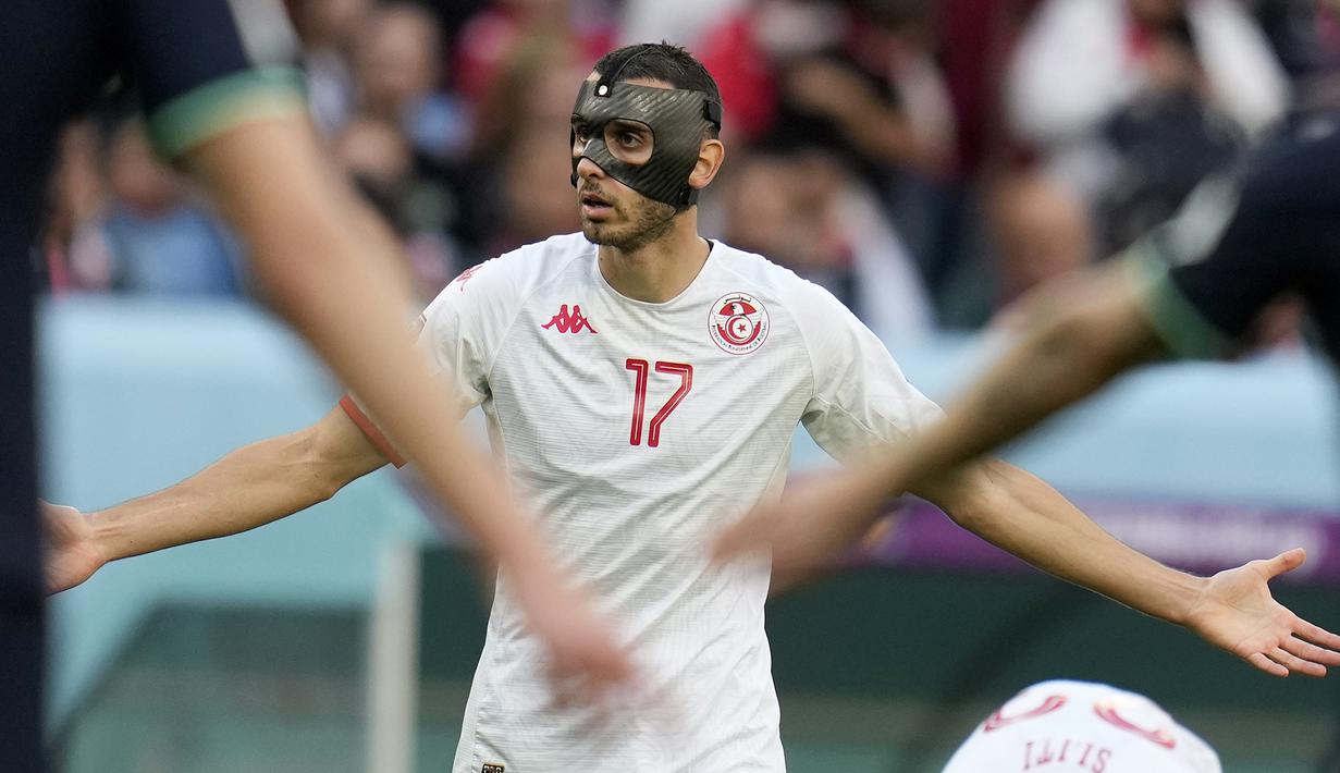Ellyes Skhiri. Gelandang bertahan Tunisia berusia 27 tahun ini telah menjalani dua laga di Grup D melawan Denmark pada matchday pertama (22/11/2022) dan kontra Australia pada matchday kedua (26/11/2022) dengan selalu menggunakan topeng dan tampil penuh selama 90 menit. Hasilnya, Tunisia ditahan imbang 0-0 oleh Denmark dan kalah 0-1 dari Australia. Tunisia pun sementara menghuni dasar klasemen Grup D. (AP/Ricardo Mazalan)