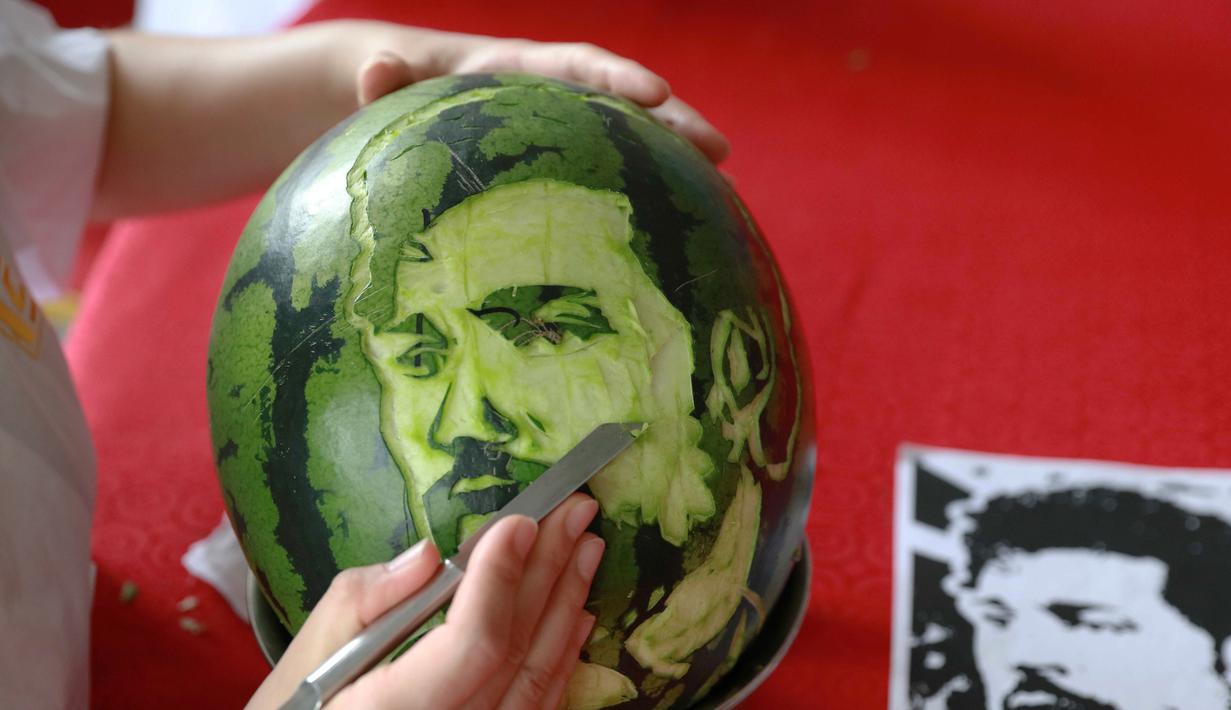 Seorang siswa sekolah menengah mengukir wajah pemain sepak bola Mesir, Mohamed Salah pada buah semangka di Shenyang, Provinsi Liaoning, China, Senin (9/7). (AFP)