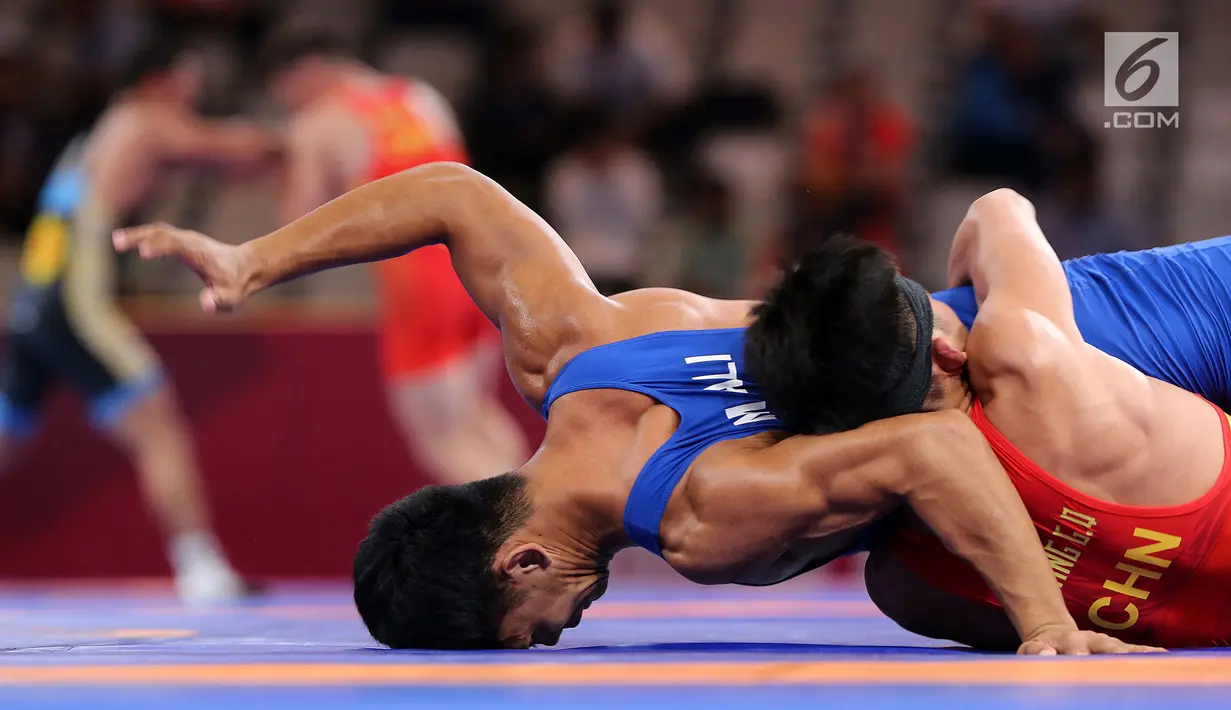 Pegulat China Zhang Gaoquan mengunci Muhammad Aliansyah dari Indonesia saat bertarung pada kelas putra 67 Kg Asian Games 2018 di arena gulat JCC Senayan, Selasa (21/8). Aliansyah kalah atas lawanya dengan skor 0-7. (Liputan6.com/Fery Pradolo)