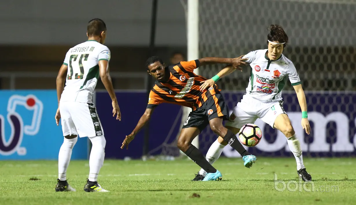 Pemain PS TNI, Hong Soon-hak berebut bola dengan pemain Perseru Serui, Franklin Rumbiak (tengah) pada laga Liga 1 2017 di Stadion Pakansari, Bogor, Minggu (18/6/2017). PS TNI menang 1-0. (Bola.com/Nicklas Hanoatubun)