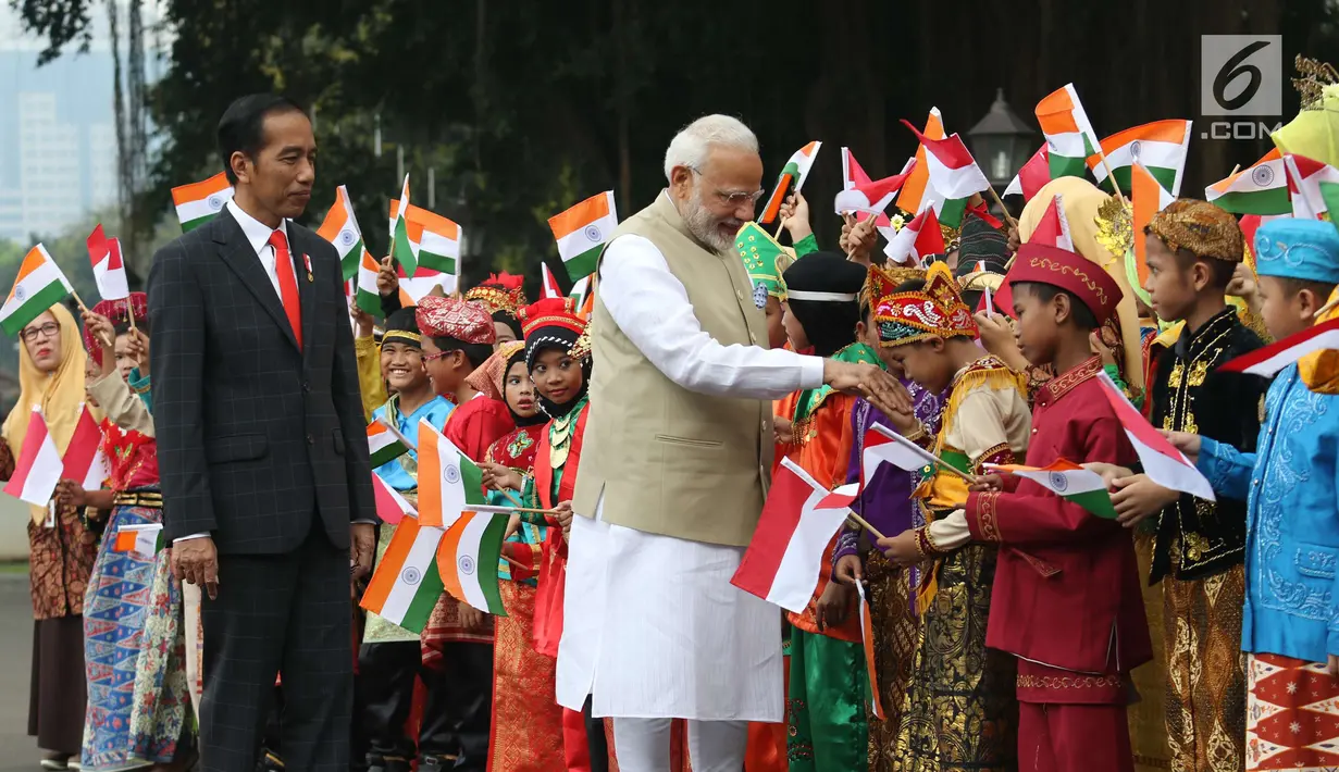 Perdana Menteri (PM) India, Narendra Modi didampingi Presiden Joko Widodo (Jokowi) bersalaman dengan murid Sekolah Dasar berpakaian adat Indonesia dalam upacara penyambutan di Istana Merdeka, Jakarta, Rabu (30/5). (Liputan6.com/Angga Yuniar)
