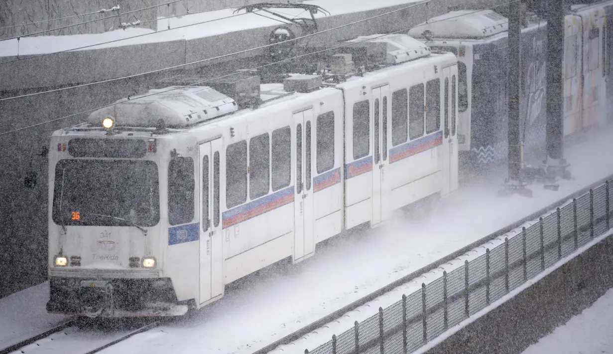 Kereta rel ringan Distrik Transportasi Regional menuju selatan di sepanjang Interstate 25 di Steele Street di tengah pusaran salju saat badai musim dingin yang membawa angin kencang dan salju lebat bergerak melintasi antar pegunungan Barat di Denver (27/1/2022). (AP Photo/David Zalubowski)