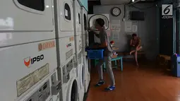 Petugas membantu konsumen menaruh cucian di sebuah laundry koin di Jakarta, Sabtu (8/6/2019). Pada libur Lebaran, jasa laundry ramai didatangi konsumen dengan sekali mencuci dibutuhkan dua koin seharga Rp 30 ribu. (merdeka.com/Imam Buhori)