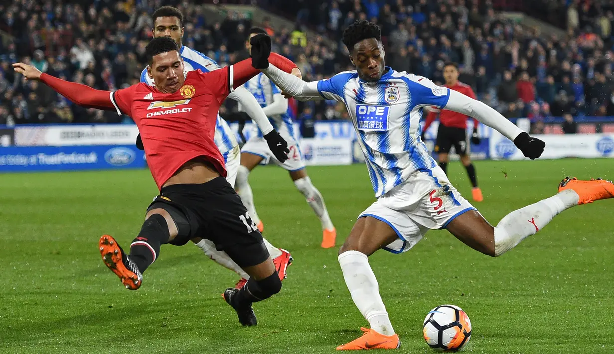 Bek Manchester United, Chris Smalling (kiri) menutup ruang tembak pemain Huddersfield, Terence Kongolo pada putaran kelima Piala FA di John Smith stadium, Huddersfield, (17/2/2018). Manchester United menang 2-0. (AFP/Oli Scarff)