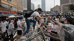 Pengunjuk rasa melewati pagar saat berkumpul di luar gedung parlemen di Hong Kong, Rabu (12/6/2019). Ribuan pengunjuk rasa memblokir pintu masuk ke kantor pusat pemerintah Hong Kong untuk memprotes RUU Ekstradisi. (AP Photo/Kin Cheung)