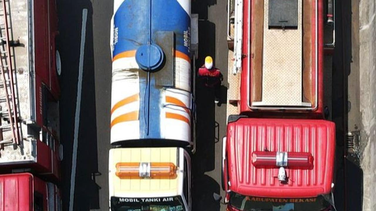 Petugas gabungan dengan sejumlah mobil pemadam saat melakukan pemadaman  asap sisa kebakaran TPS di samping Tol Cibitung-Cilincing.