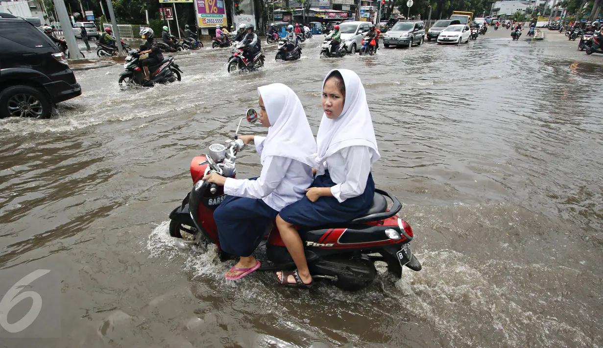 Dua orang pelajar berusaha menerobos banjir yang merendam Jalan Panjang, Jakarta Barat, Jumat (26/2). Hujan yang mengguyur wilayah Jakarta membuat sejumlah titik terendam banjir dengan ketinggian sekitar 20 cm - 1 meter. (Liputan6.com/ Immanuel Antonius)