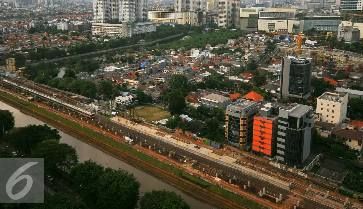 Pemandangan dari atas, pekerja tengah mengerjakan jalur kereta Api Bandara di Jakarta, Rabu (28/12). Dua rangkaian kereta itu merupakan bagian dari 10 rangkaian yang nantinya akan dioperasikan untuk Kereta Bandara Soetta. (Liputan6.com/Angga Yuniar)