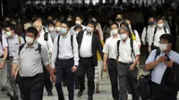 Komuter yang mengenakan masker berjalan di lorong selama jam sibuk di Stasiun Shinagawa, Tokyo, Senin (12/7/2021). Otoritas Jepang menempatkan Tokyo di bawah keadaan darurat Covid-19 keempat sebagai upaya menahan lonjakan kasus infeksi virus Corona dari Senin hingga 22 Agustus. (AP /Eugene Hoshiko)