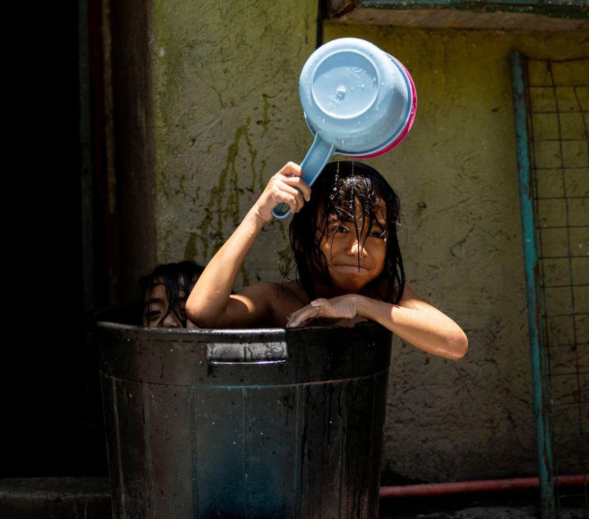 Dua orang anak berendam di sebuah ember ketika panas menyengat menyerang Kota Manila, Filipina, Kamis (25/4/2024). Panas ekstrem dengan suhu hampir menyentuh 50 derajat Celcius melanda sejumlah negara di Asia Tenggara, seperti Thailand dan Filipina.&nbsp;