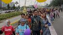 Sejumlah orang yang mengenakan batik berjalan di catwalk sepanjang Jalan Jenderal Sudirman, Jakarta, Minggu (2/10/2022). Kegiatan yang diikuti ratusan orang ini diselenggarakan oleh Bank Mandiri untuk menyambut Hari Batik Nasional yang jatuh setiap tanggal 2 Oktober 2022. (Liputan6.com/Faizal Fanani)
