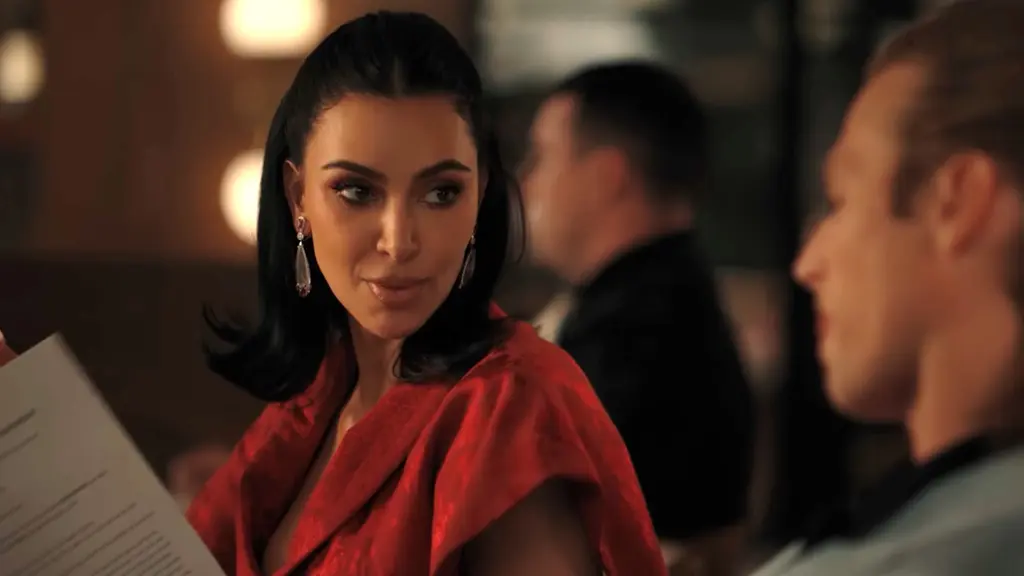 Dalam Episode 7 All's Fair, Kim Kardashian mengenakan baju berwarna merah. Ia tampil dengan gaya rambut kuncir belakangnya. [Dok. Chopard]