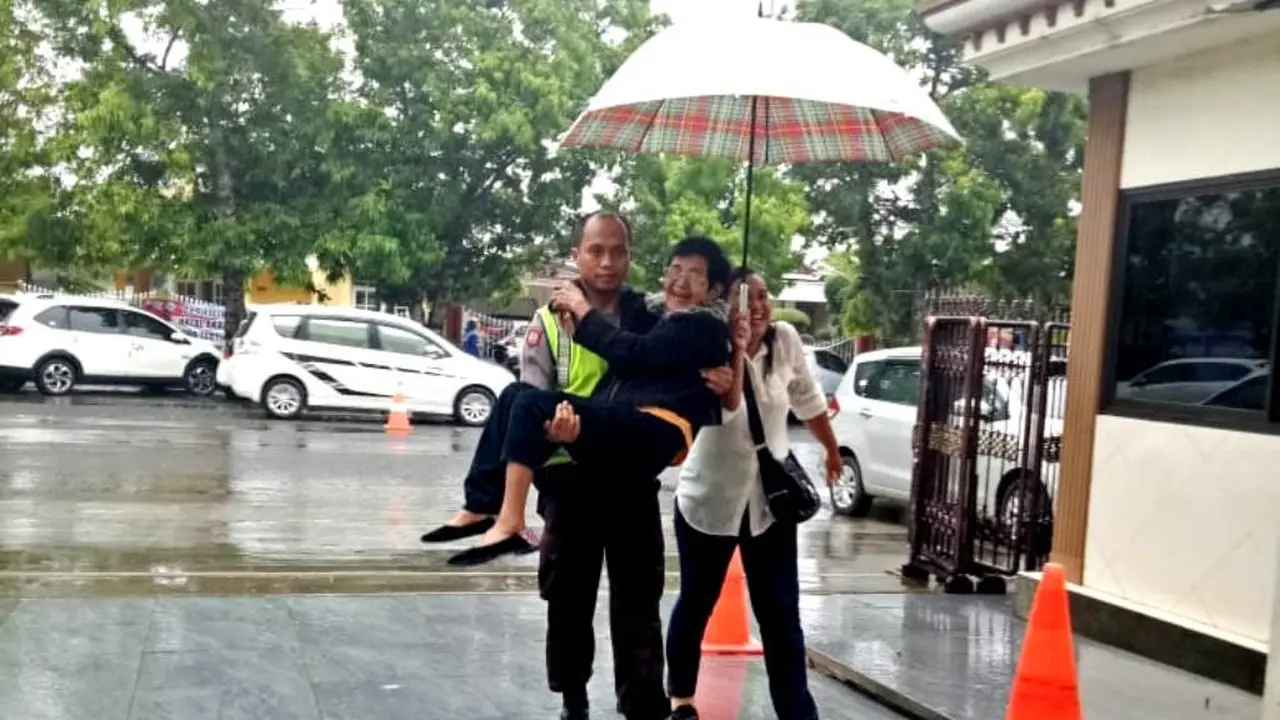 Seorang polisi menggendong nenek yang kehujanan ketika menyeberang ke gereja Maranatha, Cilacap. (Foto: Liputan6.com/Polres Cilacap/Muhamad Ridlo)