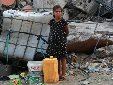 Seorang anak perempuan Palestina bersiap mengisi wadah plastik dengan air di titik distribusi di Khan Yunis di Jalur Gaza selatan pada 17 Oktober 2024. (BASHAR TALEB/AFP)