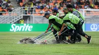 Petugas di Jakarta International Stadium (JIS) menguras lapangan yang tergenang akibat guyuran hujan deras jelang pertandingan Brasil Vs Argentina pada perempat final Piala Dunia U-17 2023, Jumat (24/11/2023). (Bola.com/Bagaskara Lazuardi)