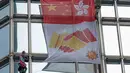 Alain Robert yang dijuluki 'French Spiderman' mengibarkan bendera China dan Hong Kong di gedung pencakar langit Cheung Kong Center, Hong Kong, Jumat (16/8/2019). Selama pendakian, Alain Robert memasang spanduk yang menampilkan bendera Hong Kong dan China. (AP Photo/Vincent Thian)