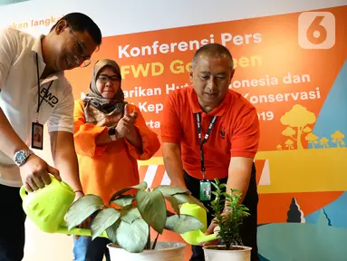 Director & Chief of Proposition & Sharia Officer FWD Life Ade Bungsu (kiri) dan Direktur Human Capital & Legal WWF-Indonesia, Apin Aviyan (kanan) menyiram pohon pada kampanye Go Green di Jakarta, Rabu (4/12/2019). Kampanye Go Green membantu nasabah memahami manfaat di balik e-Policy. (Liputan6.com)