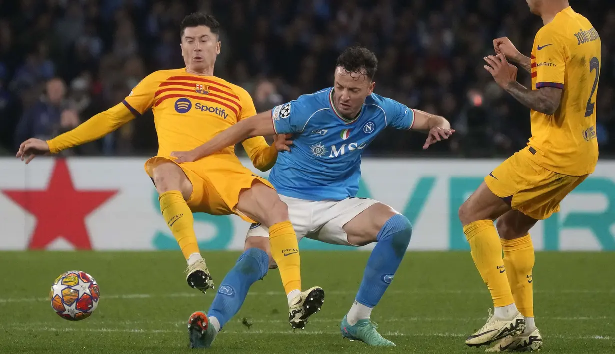 Pemain Napoli, Amir Rrahmani (tengah) berebut bola dengan pemain Barcelona, Robert Lewandowski (kiri) pada laga leg pertama 16 besar Liga Champions 2023/2024 di Diego Armando Maradona stadium, Napoli, Italia, Kamis (22/02/2024) dini hari WIB. (AP Photo/Gregorio Borgia)