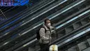 Seorang pria yang mengenakan masker dengan barang bawaannya menaiki eskalator di Stasiun Kereta Api Barat di Beijing, Jumat (6/1/2023). China berupaya meminimalkan kemungkinan wabah COVID-19 yang lebih besar selama kesibukan perjalanan Tahun Baru Imlek bulan ini menyusul berakhirnya sebagian besar langkah-langkah pencegahan pandemi. (AP Photo/Wayne Zhang)