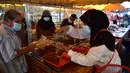Orang-orang memakai masker di kios-kios yang dikelilingi oleh pelindung plastik di pasar, sebagai bagian dari upaya untuk menghentikan penyebaran virus corona Covid-19, selama bulan suci Ramadhan di provinsi selatan Thailand, Narathiwat (17/4/2021). (AFP/Madaree Tohlala)
